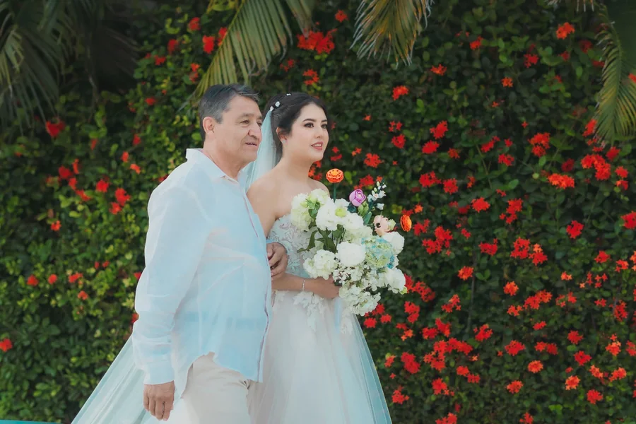 Pareja de novios frente a un muro de flores tropicales