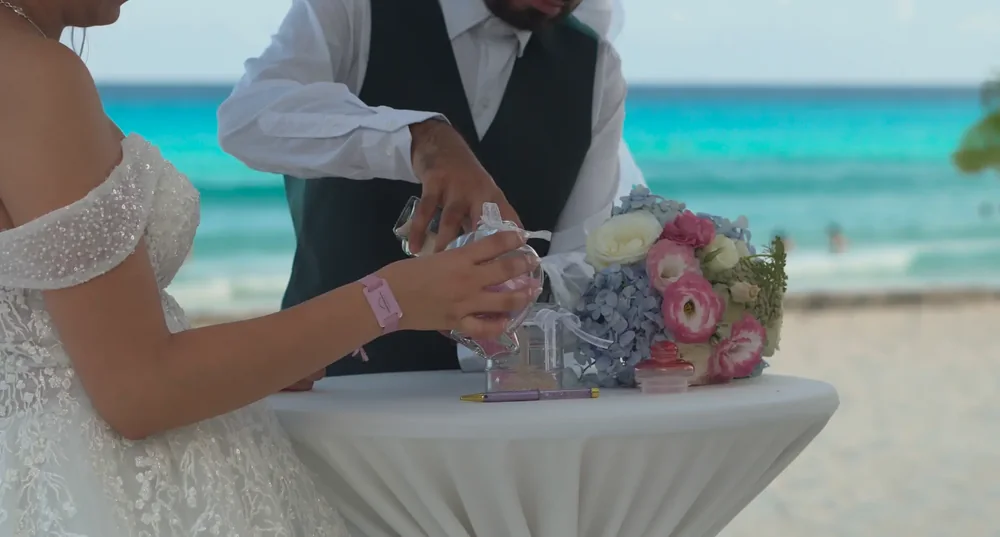 Ritual de boda con manos y flores frente al mar