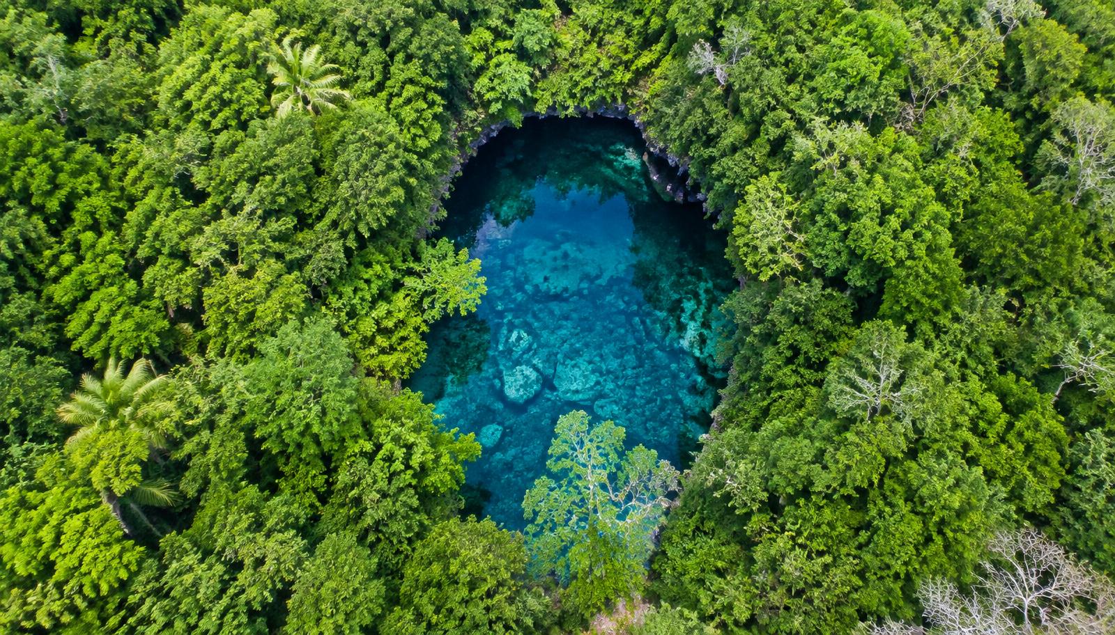 Vista aérea de la selva maya con un cenote turquesa