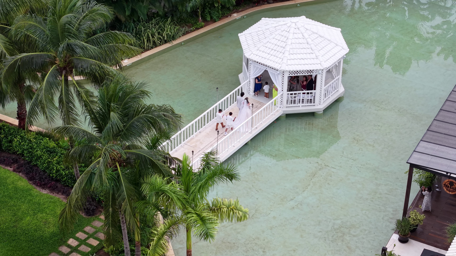 Vista aérea de un gazebo blanco sobre el agua con puente