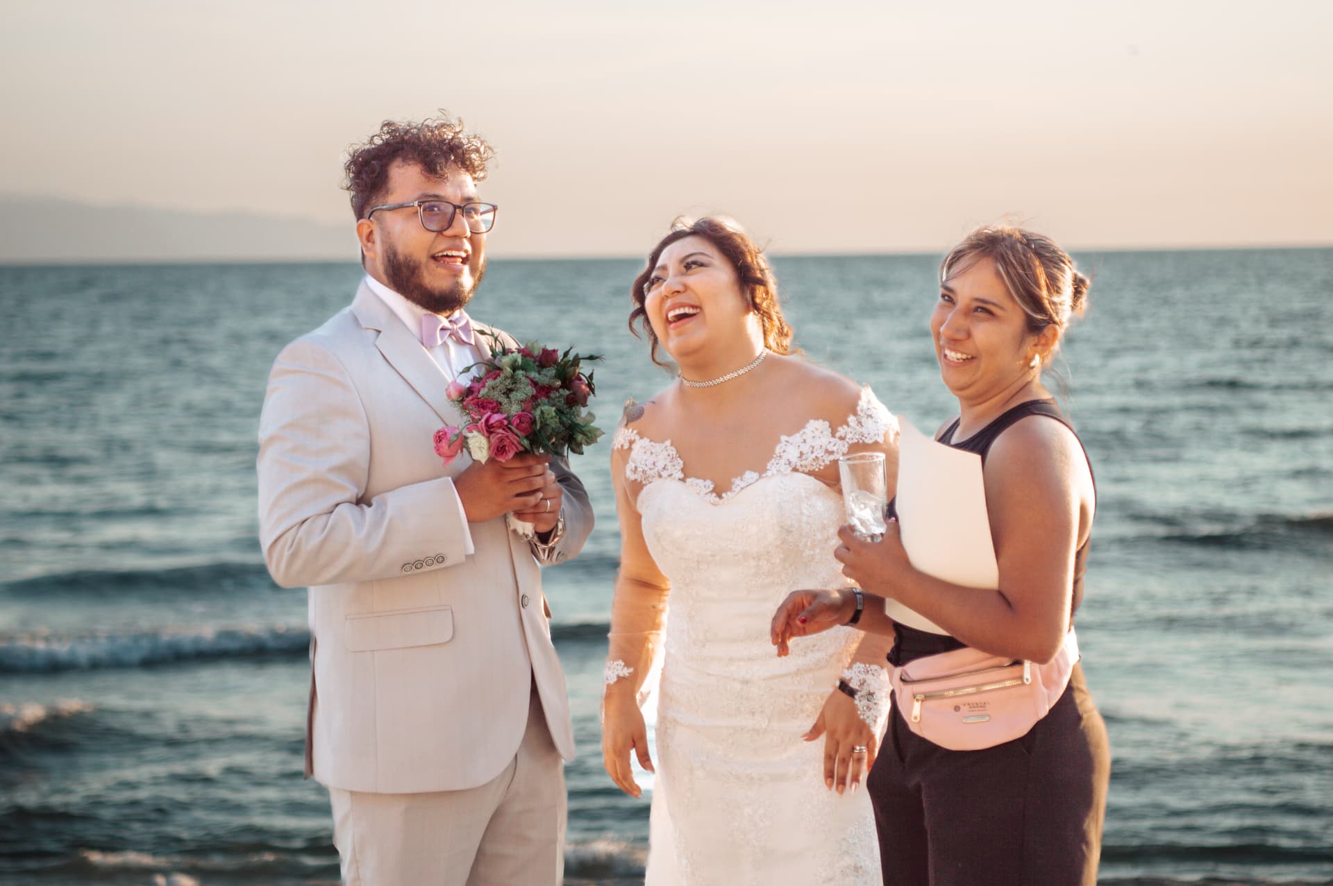 Pareja de novios con su coordinadora en una boda frente al mar